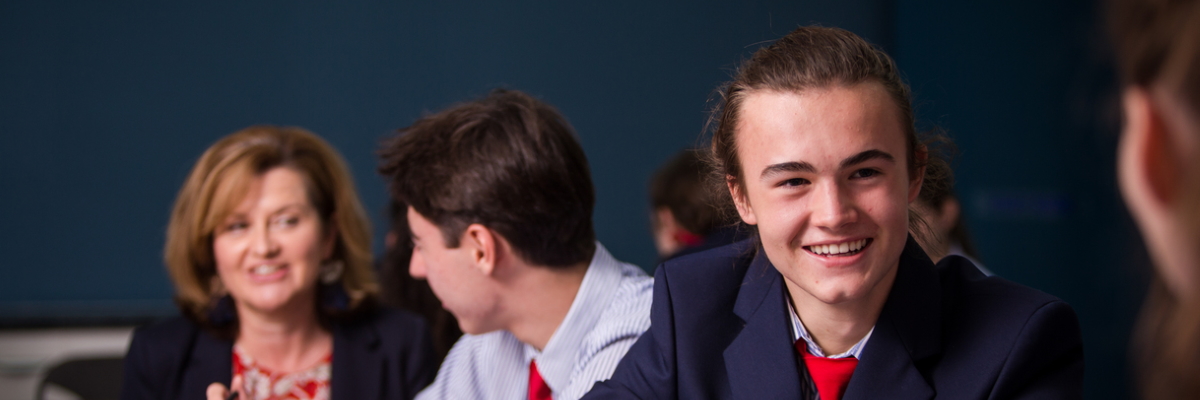 Student in discussion with two staff members in background.