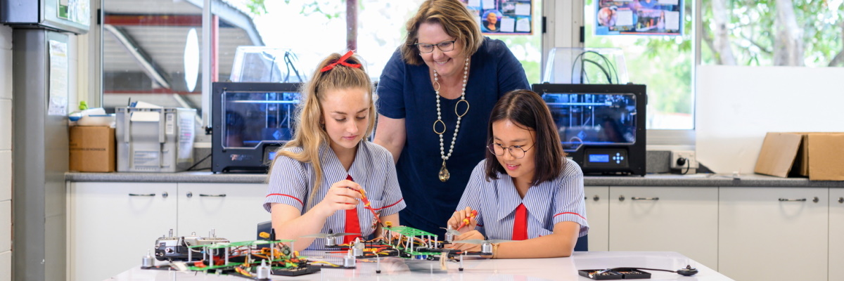 Two students enjoying robotics and a teacher supervising
