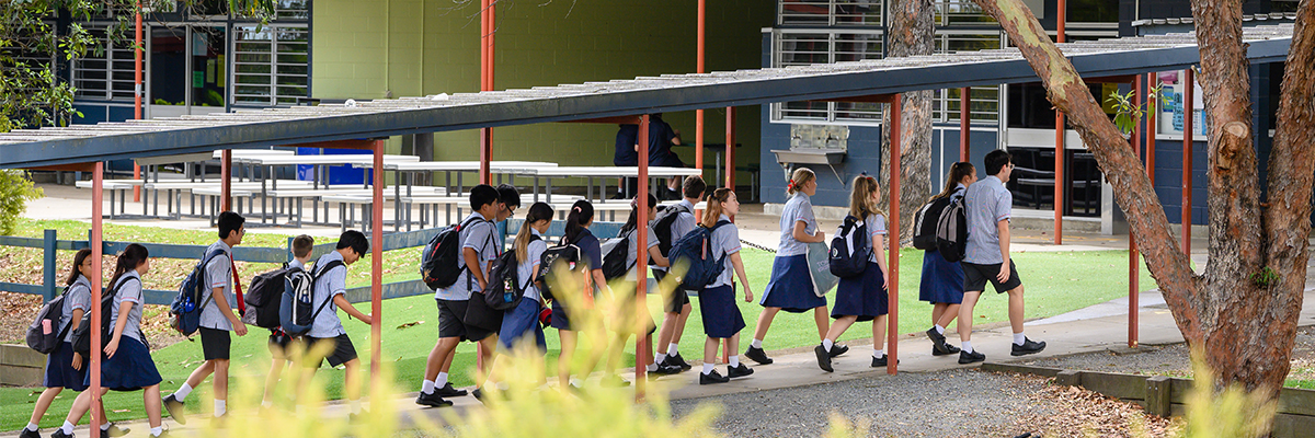Students walking through school campus with their backpacks.
