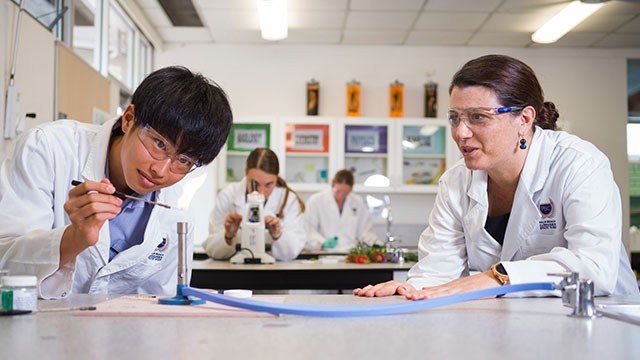 Student doing a science experiment with a supervising teacher