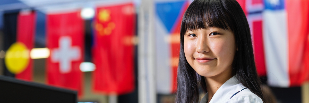 A student in front of flags from around the world