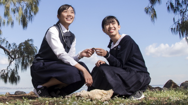 Two students outside sitting on grass