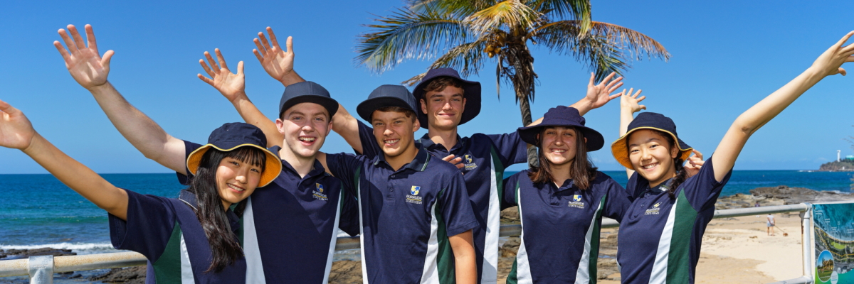 A group of students posing by the shoreline